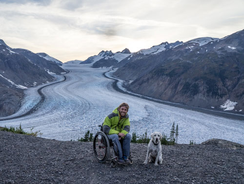 Kirk with his dog in front of an Alaskan glacier