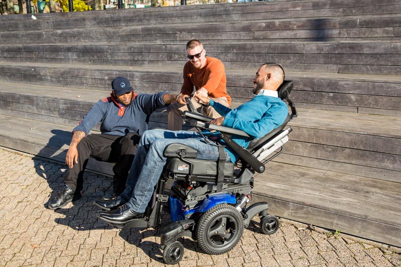A man using a power wheelchair hanging out with his friends