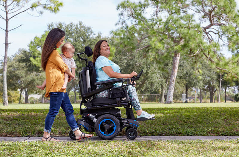 A woman using her power wheelchair with her family