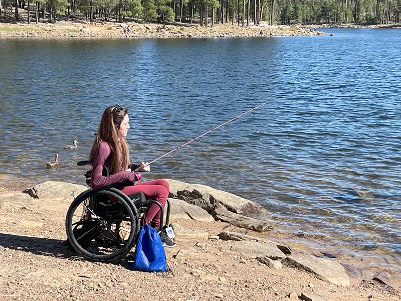 A woman using a wheelchair fishing by a lake