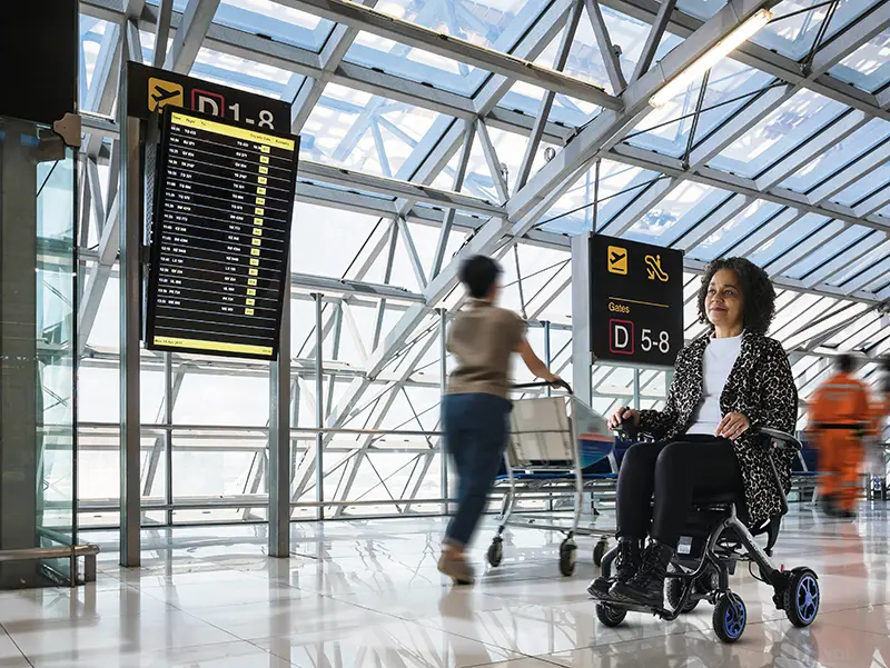 A woman using a power wheelchair to navigate an airport